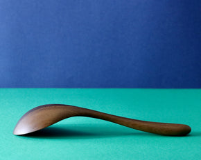 Side profile of a Handmade Walnut Wood Soup Ladle with green and blue background