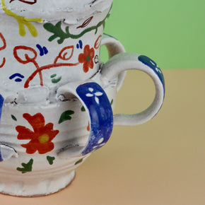 Handmade Ceramic Pentref Jug by Elin Hughes against a green and peach background. Close up lower.