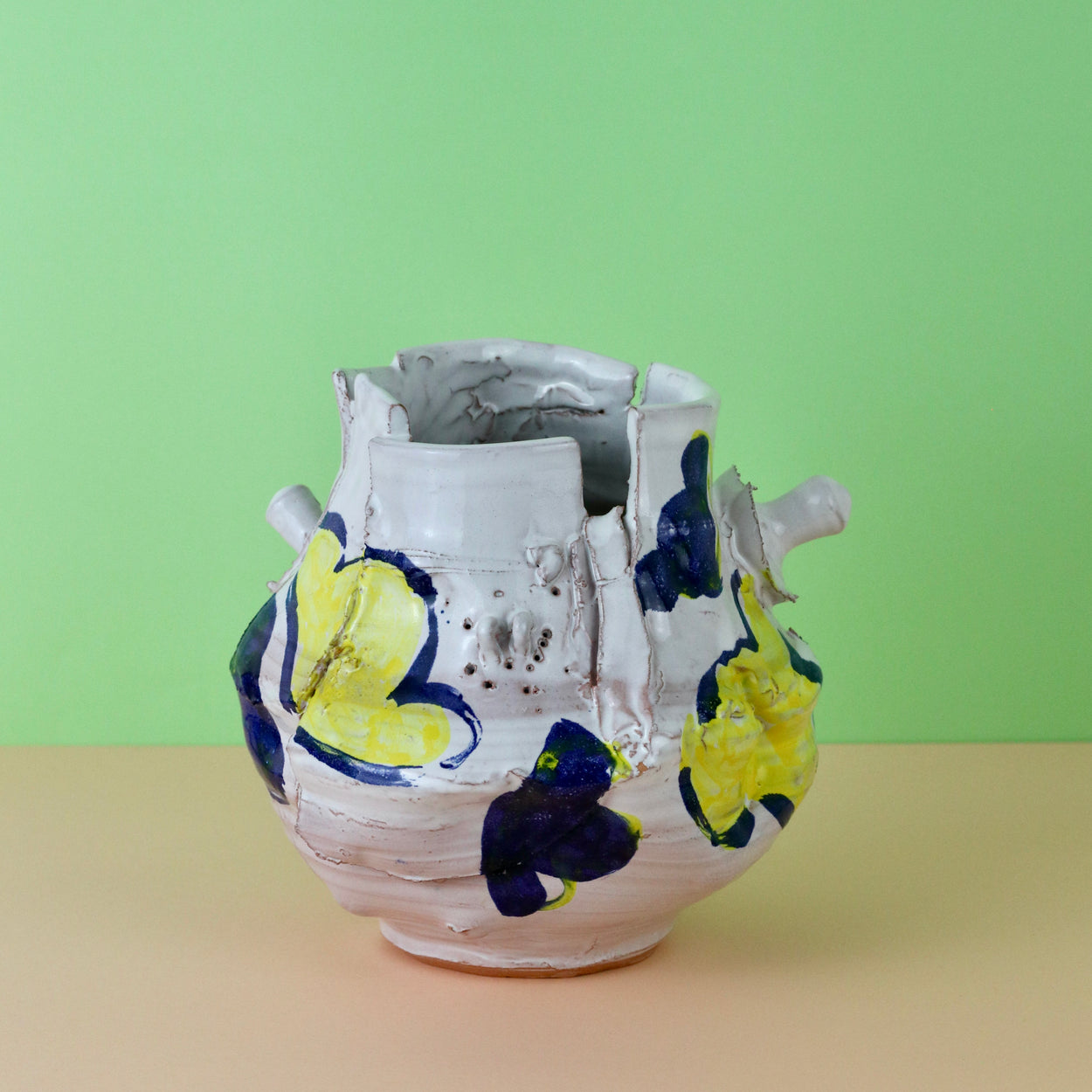 Modern Ceramic Vase by Elin Hughes against a light green and peach background.