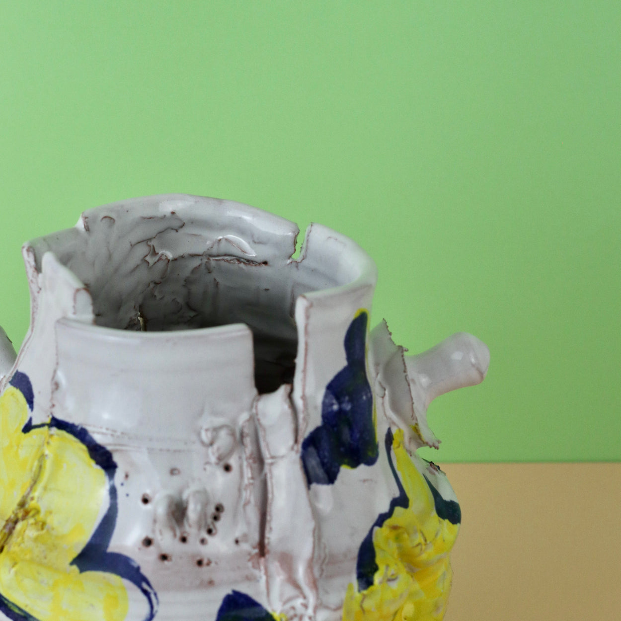 Modern Ceramic Vase by Elin Hughes against a light green and peach background. Top close up.