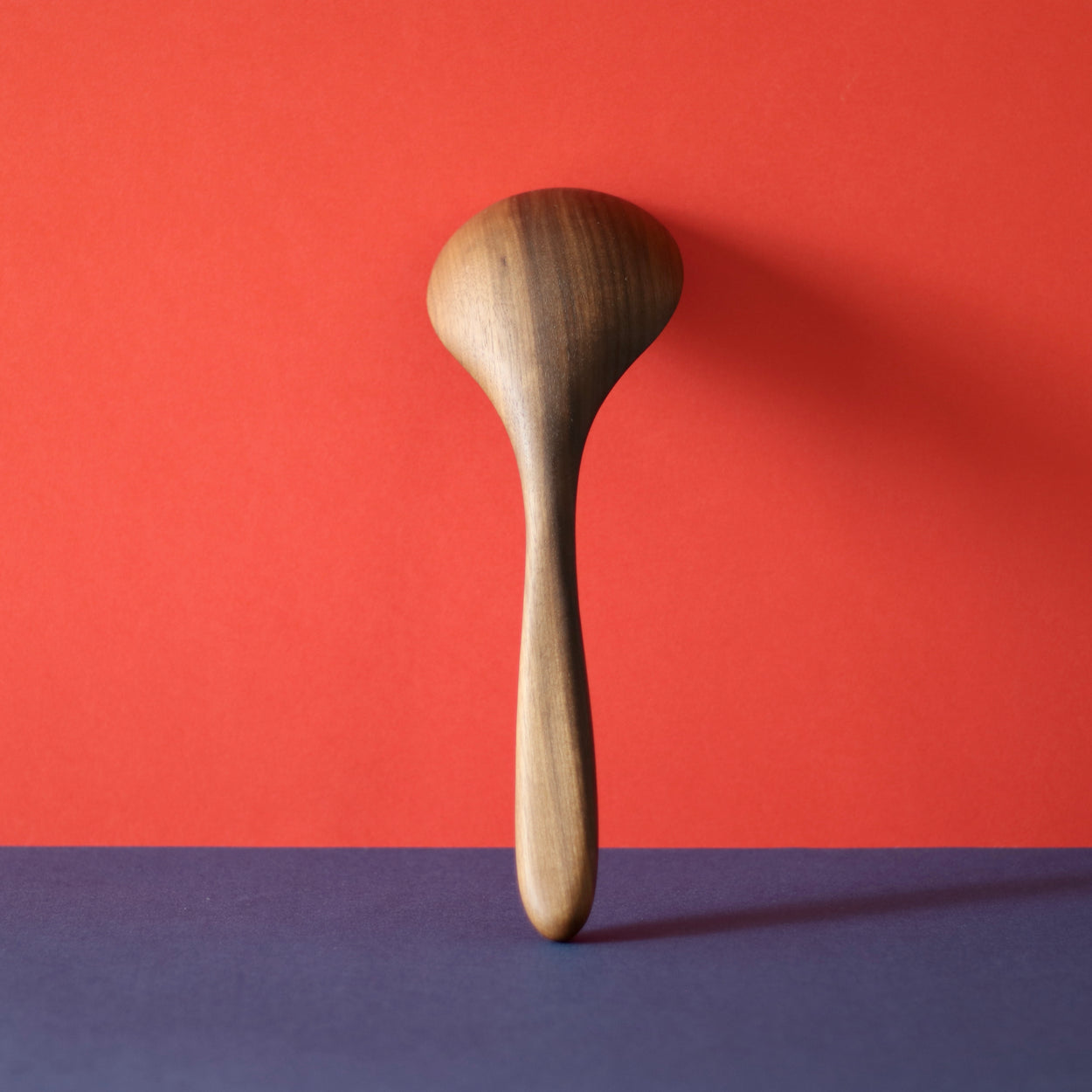 Back view of Handmade Walnut Wood Soup Ladle with red and blue background