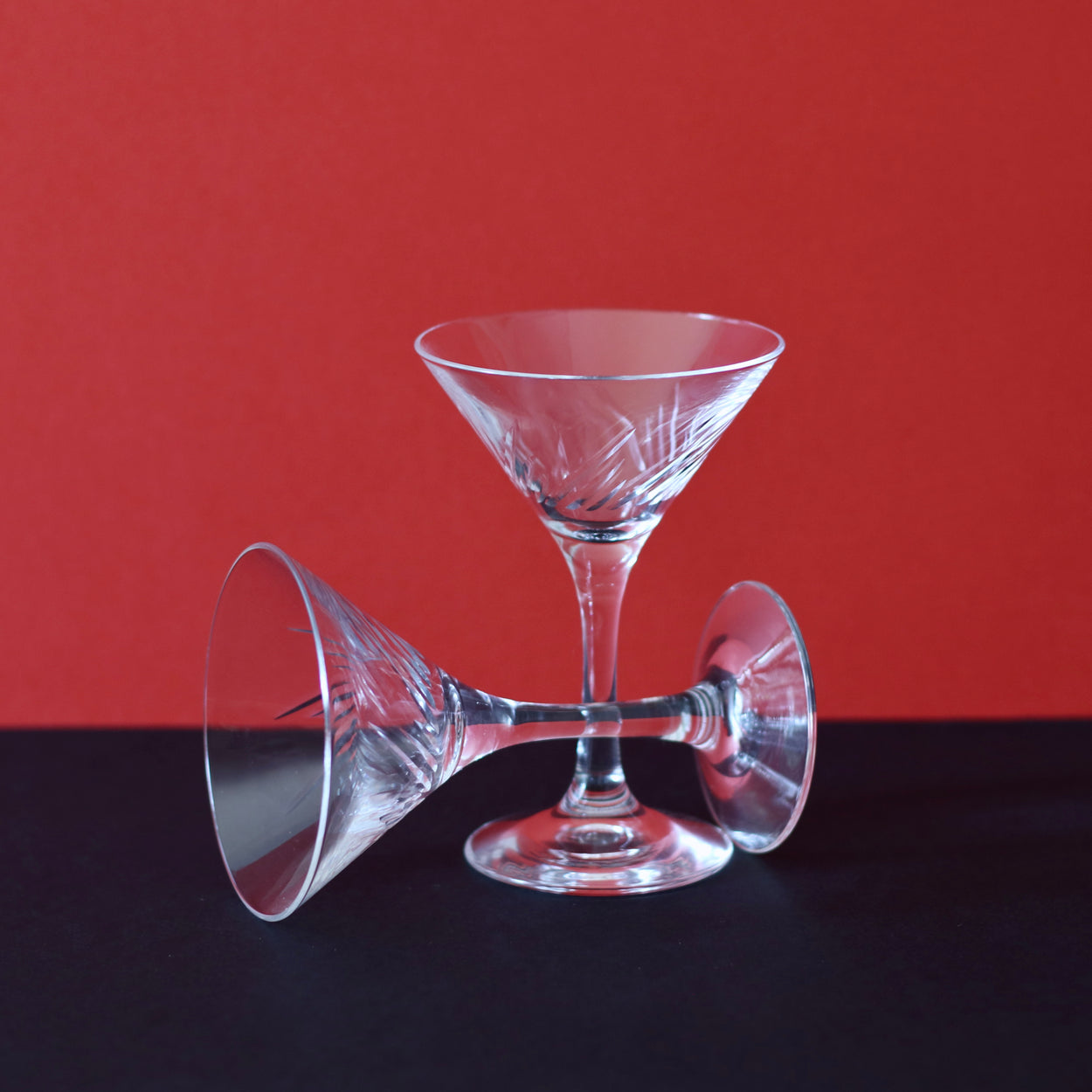 Japanese martini glasses x 2, one lying on it's side, against red and black backdrop.