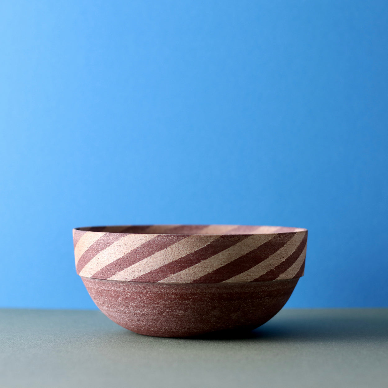 Ceramic Thin Stripe Bowl by Amanda-Sue Rope with blue green background.