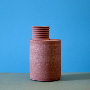 Handmade Ceramic Vase by Amanda-Sue Rope against a blue and green background.