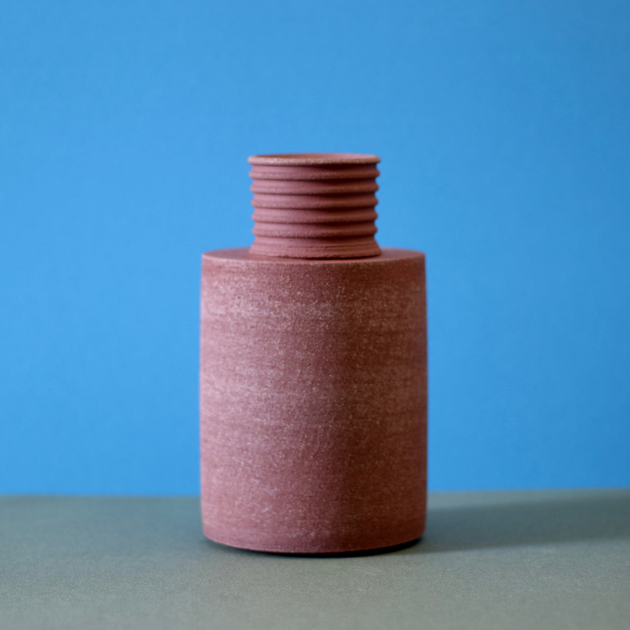 Handmade Ceramic Vase by Amanda-Sue Rope against a blue and green background.