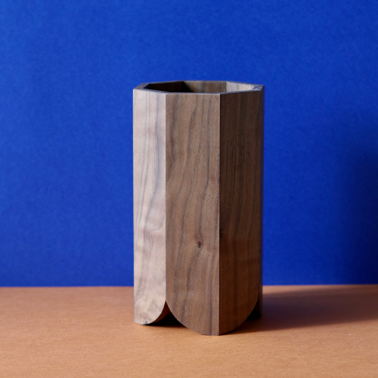 Handmade Wood Kitchen Utensil Holder in walnut against a blue and brown background.