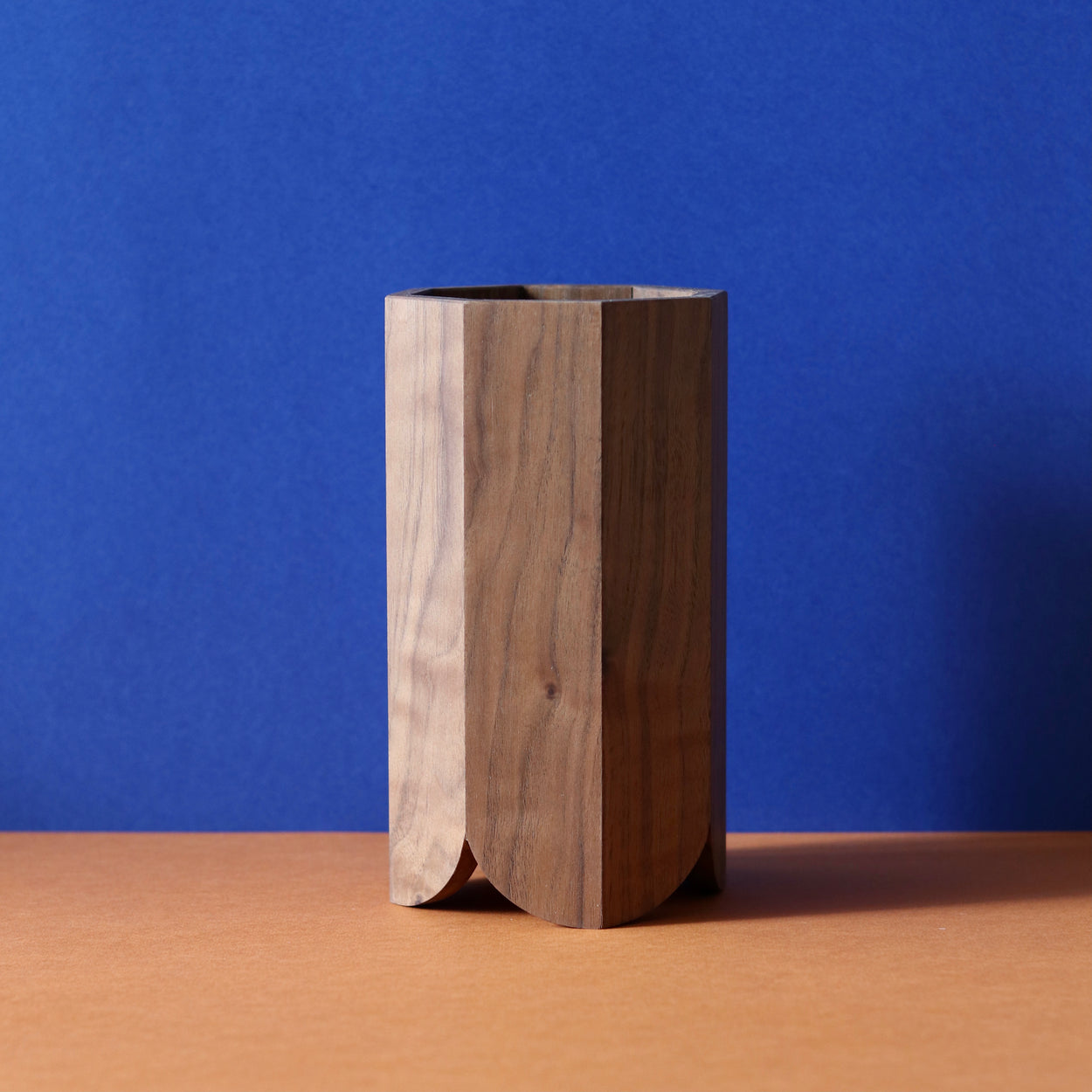 Handmade Wood Kitchen Utensil Holder in walnut against a blue and brown background.