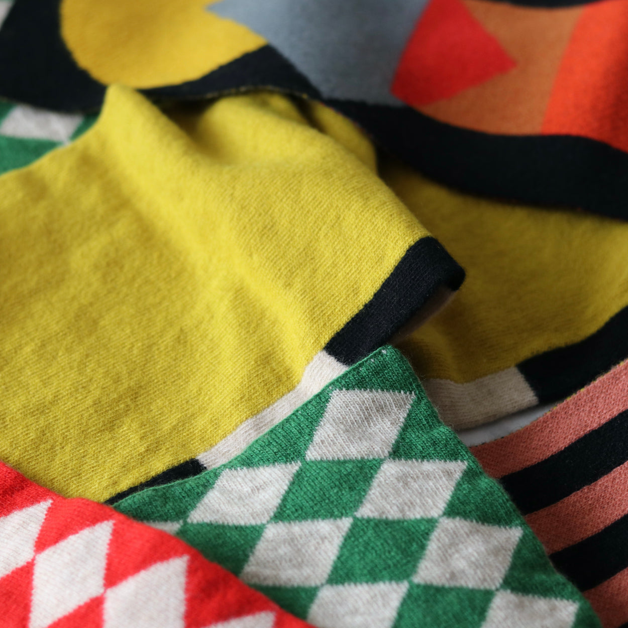 Assorted colourful Jo Gordon scarves criss crossed on top of each other.