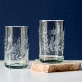 2 x Hand blown etched glass tumblers with blue and white background, on marble block.