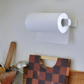 Paper Towel Roll Holder -  White mounted on wall horizontally with wood chopping boards and kitchen utensils below.