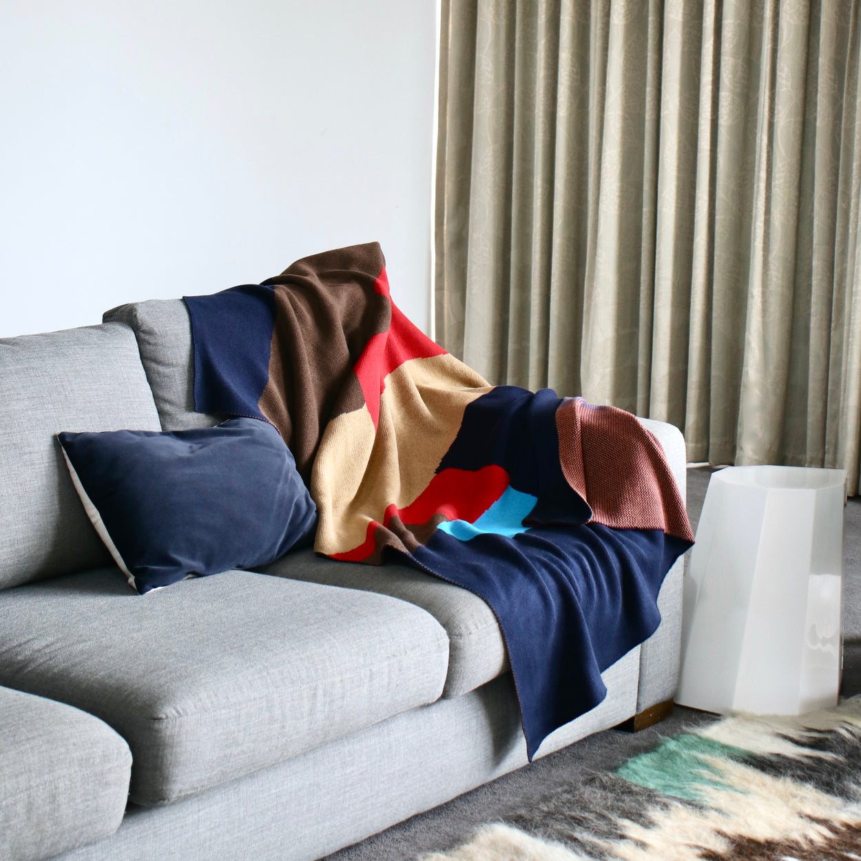Modern cotton navy blue knit throw blanket on grey sofa with blue cushion