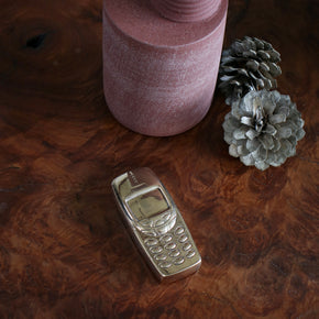 Bronze phone sculpture by Nancy Pearce sitting on a wood burl table.