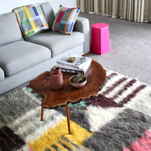 Arnold Circus Stool bedside table in Magenta Pink in colourful lounge room with sofa and rug