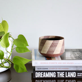 Ceramic Medium Stripe Bowl by Amanda-Sue Rope on stack of books with plant leaves