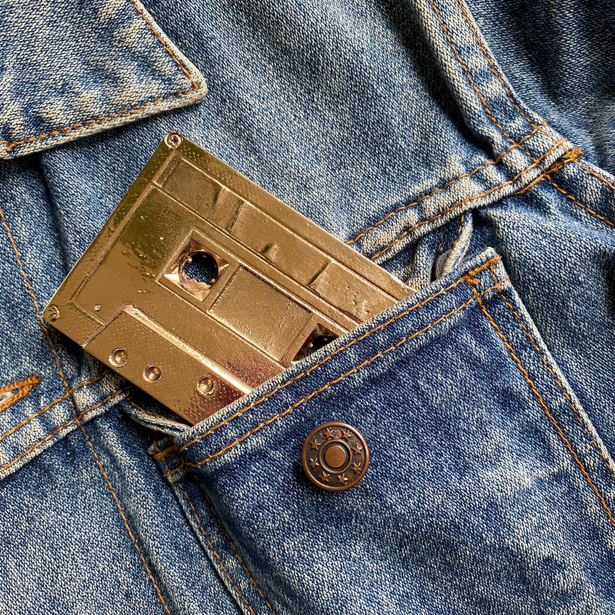 Bronze Cassette Mix Tape by Nancy Pearce half in a denim jacket pocket