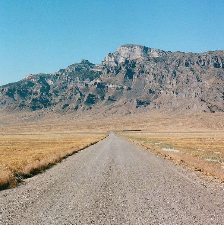 Large mountain range and gravel road landscape.