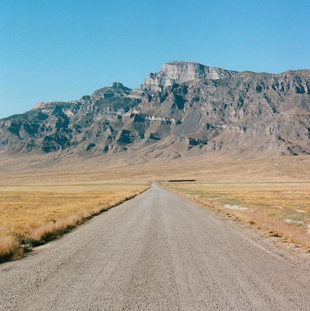 Large mountain range and gravel road landscape.