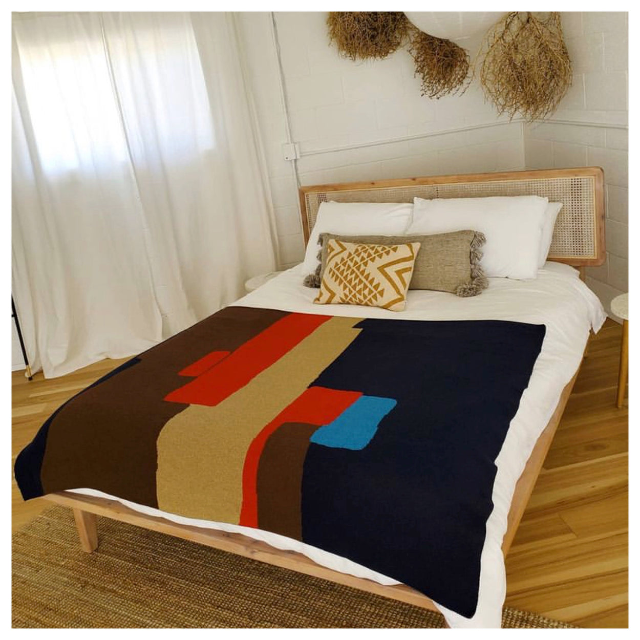 Modern Blue, red, tan and brown cotton knit throw blanket on bed from Civil Dawn Studio