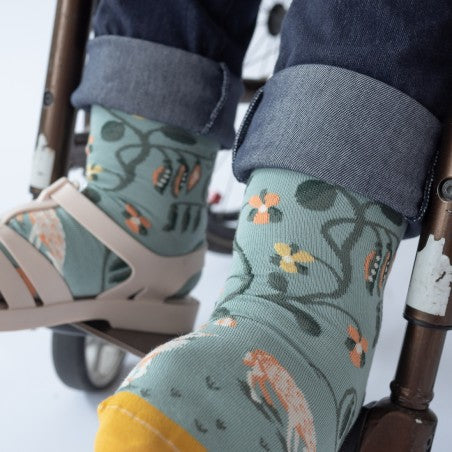 Person in wheel chair wearing Bonne Maison Bean Socks with blue jeans and jelly sandals