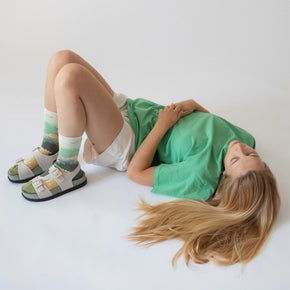 Woman lying down with knees bent in white shorts and green tshirt wearing Bonne Maison Swimmer Socks