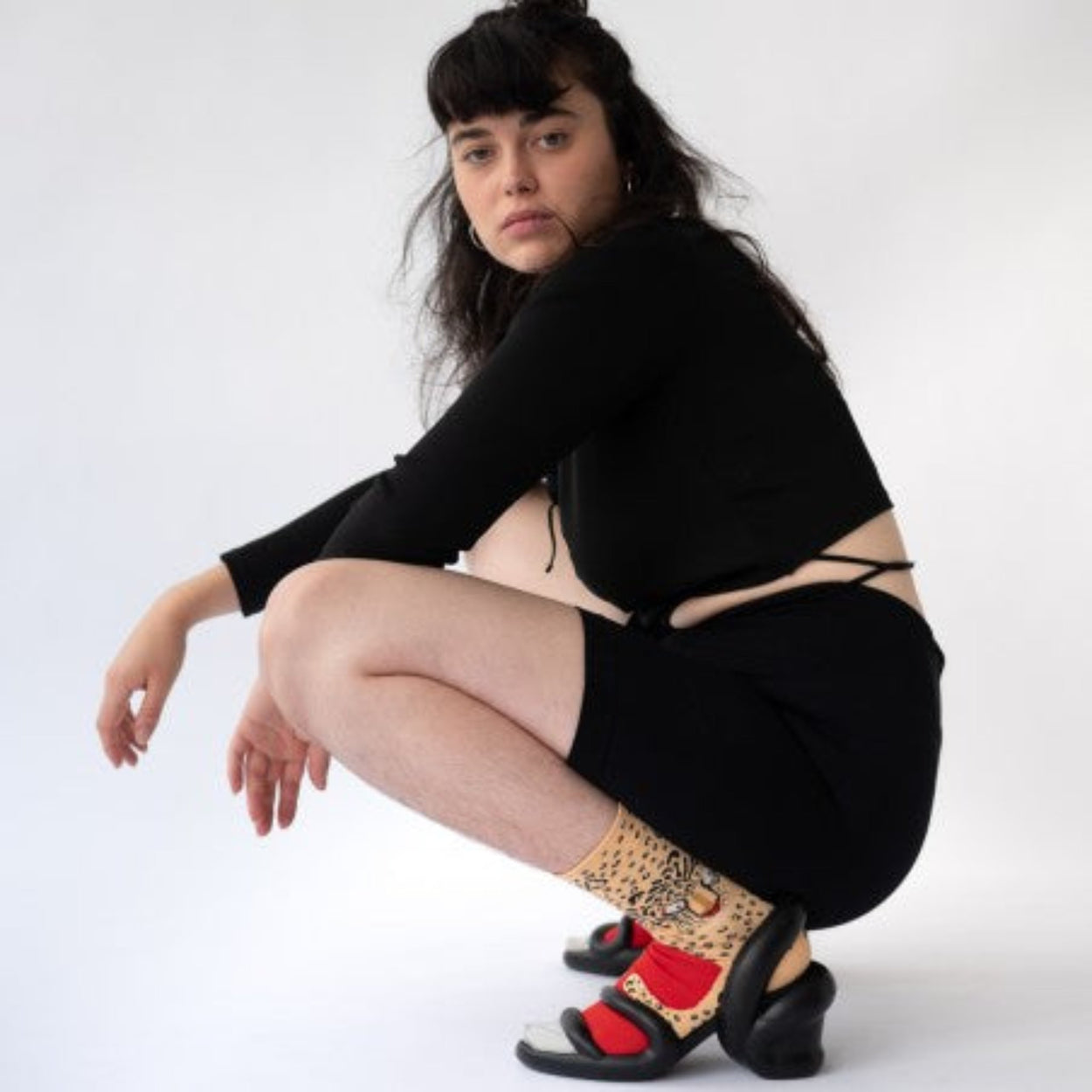 Woman in black with black heels wearing Bonne Maison Leopard Socks.